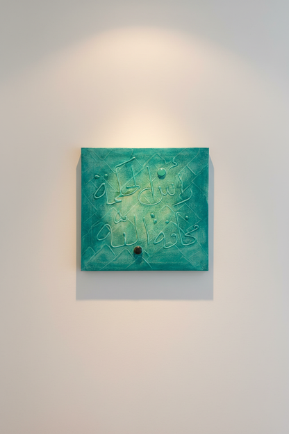 Islamic calligraphy teal quilted wall art displayed on empty white wall