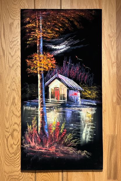 Lakeside cabin painting displayed on dark walnut wood panel wall